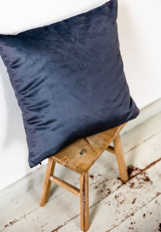 Kissen aus königsblauem Premium-Samt auf Holzhocker, schräg von oben fotografiert