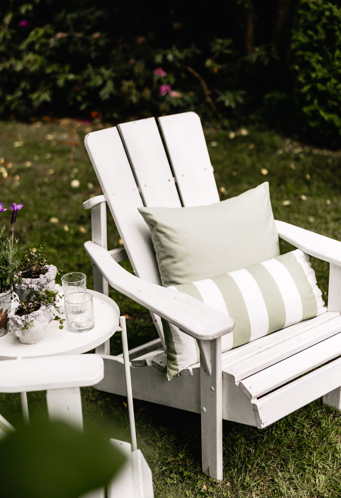 Zwei Wendekissen in sanftem Grün und Weiß auf weißem Gartenstuhl im Grünen – Outdoor-Kissen für stilvolles Entspannen im Freien
