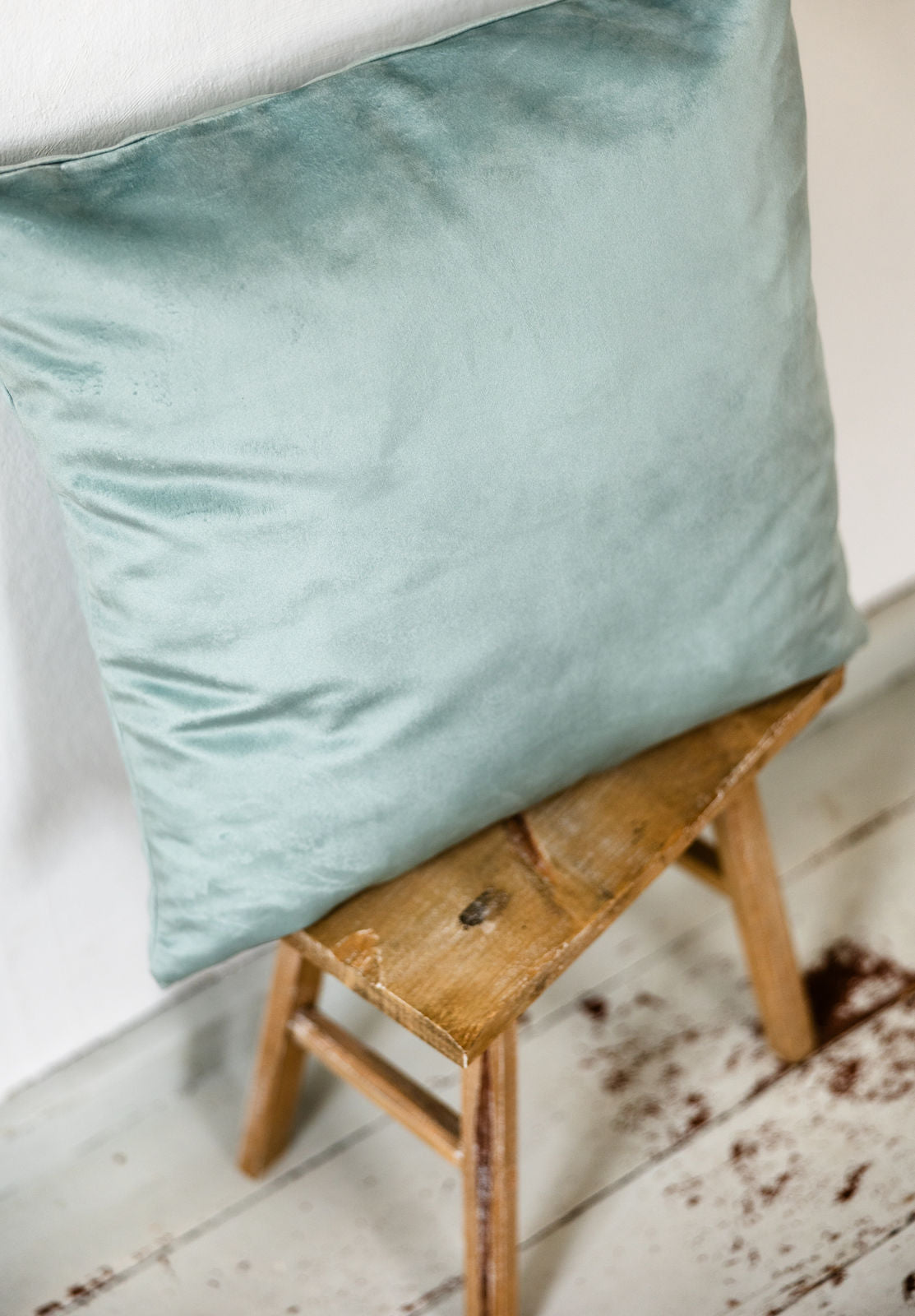 Aquablaues Premium-Samtkissen auf einem Hocker, von schräg oben fotografiert