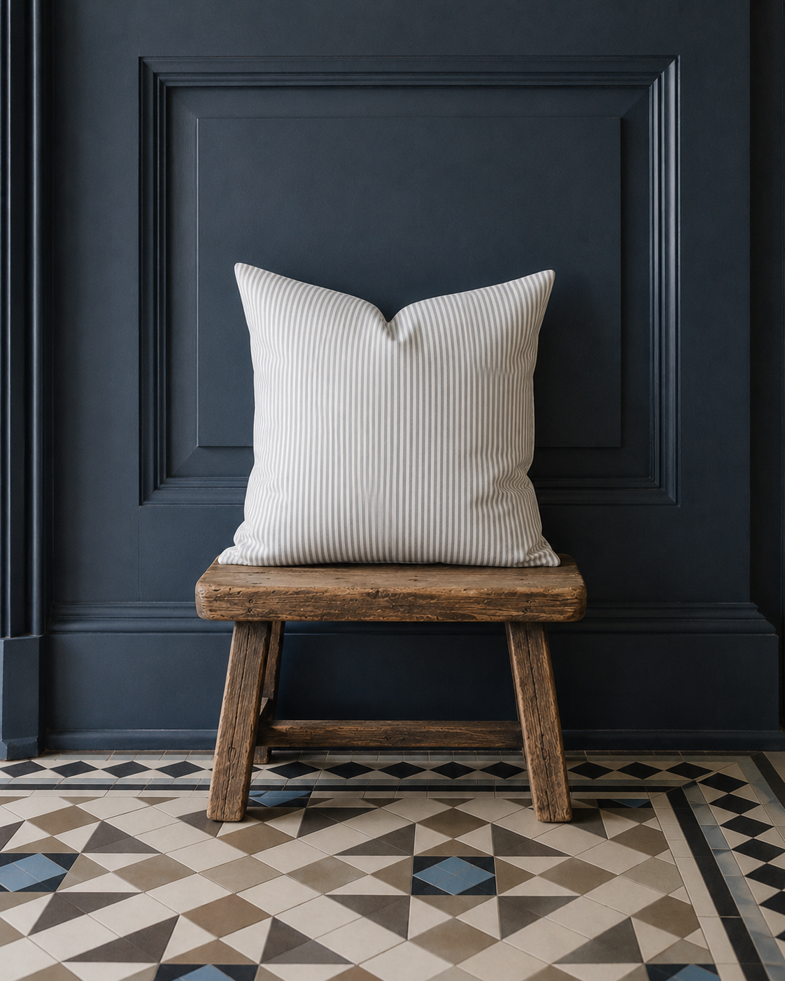 Grau Weiß gestreiftes Kissen auf Hocker vor dunkelblauer Holzpaneele mit Taupe, Beige und blauen Bodenfliesen