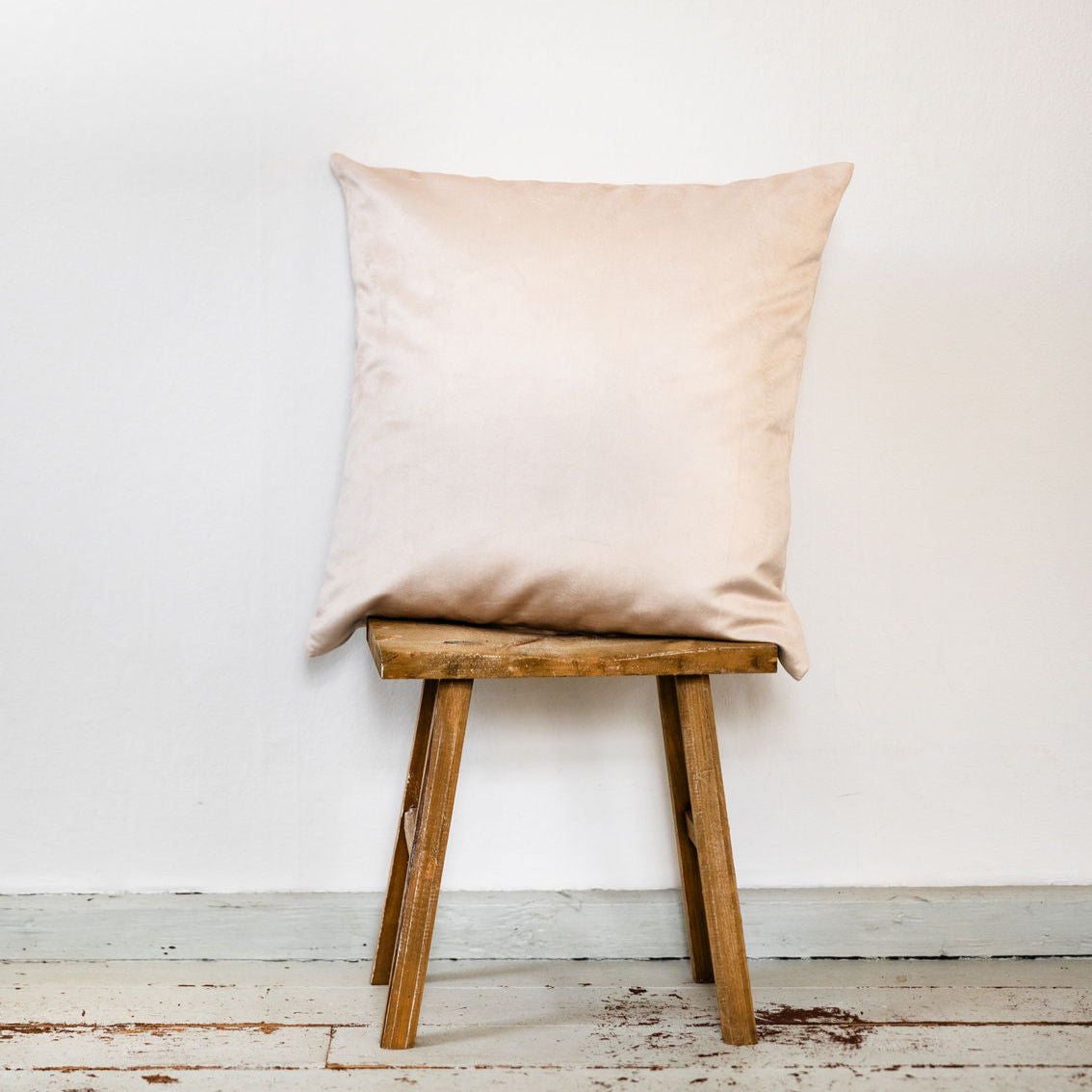 Samtkissen Beige - Premiumsamt auf Holzhocker vor weißer Wand