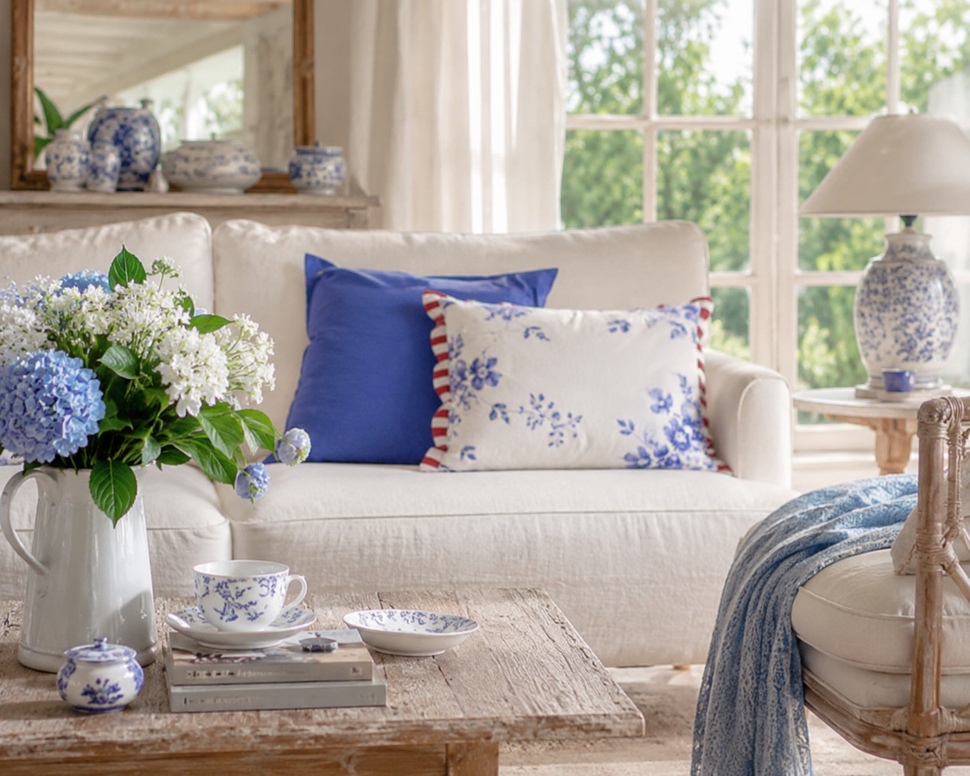 Dekokissen im Delfter Blau auf hellem Sofa im Landhausstil. Blau-weiße Kissenhüllen mit floralem Muster als stilvolle Wohnraumdekoration.