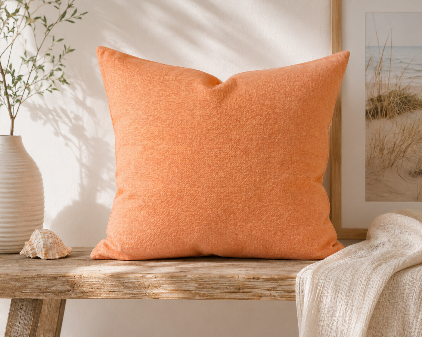 Mandarinefarbenes Dekokissen 50x50 cm auf einer Holzbank im Coastal-Living-Stil. Unifarbenes Zierkissen in warmem Orangeton für Sofa, Ferienwohnung, Strandhaus und maritimes Wohnen.