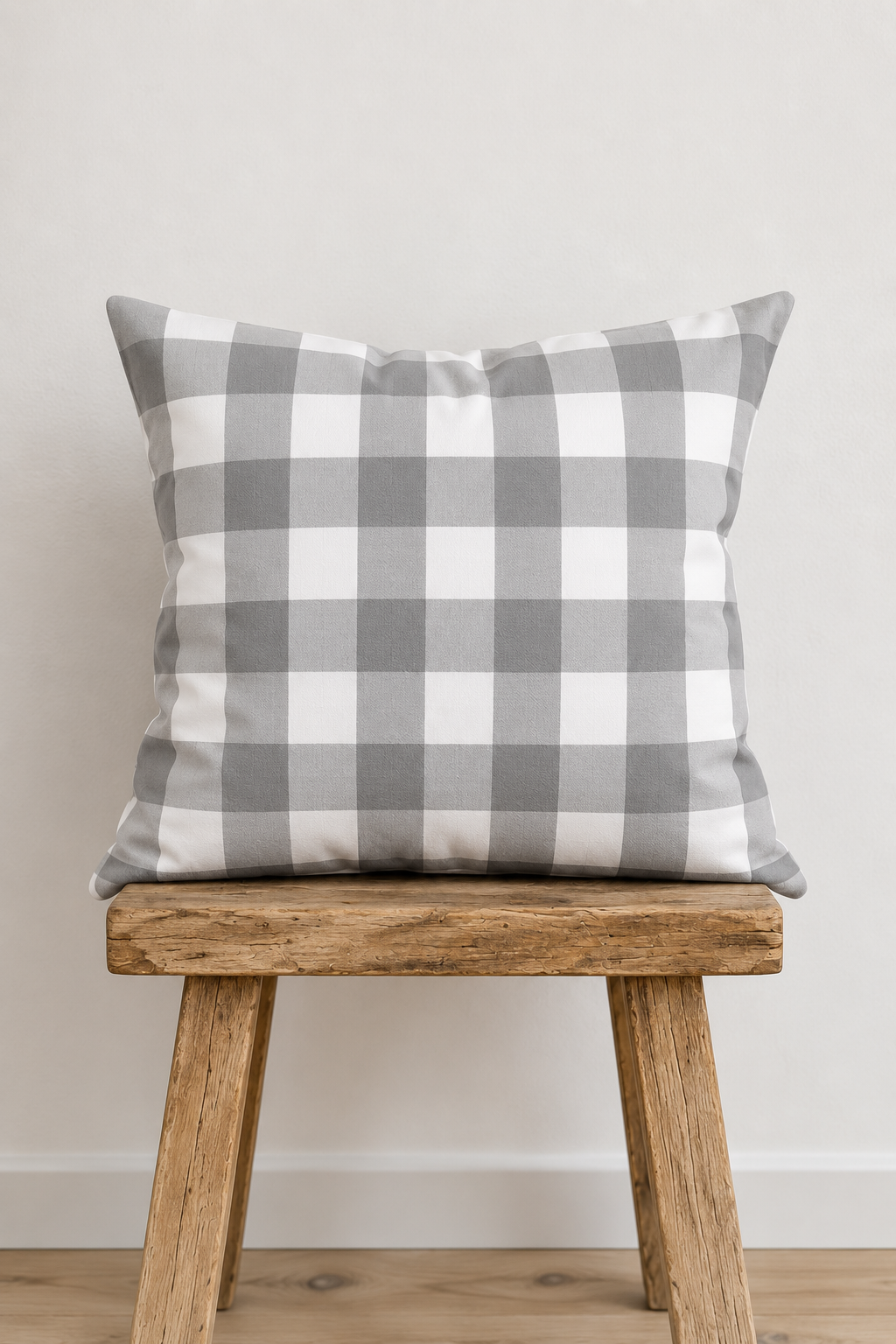 Kariertes Kissen in Grau und Weiß auf rustikalem Holzhocker – Dekokissen mit Karomuster im modernen Landhausstil