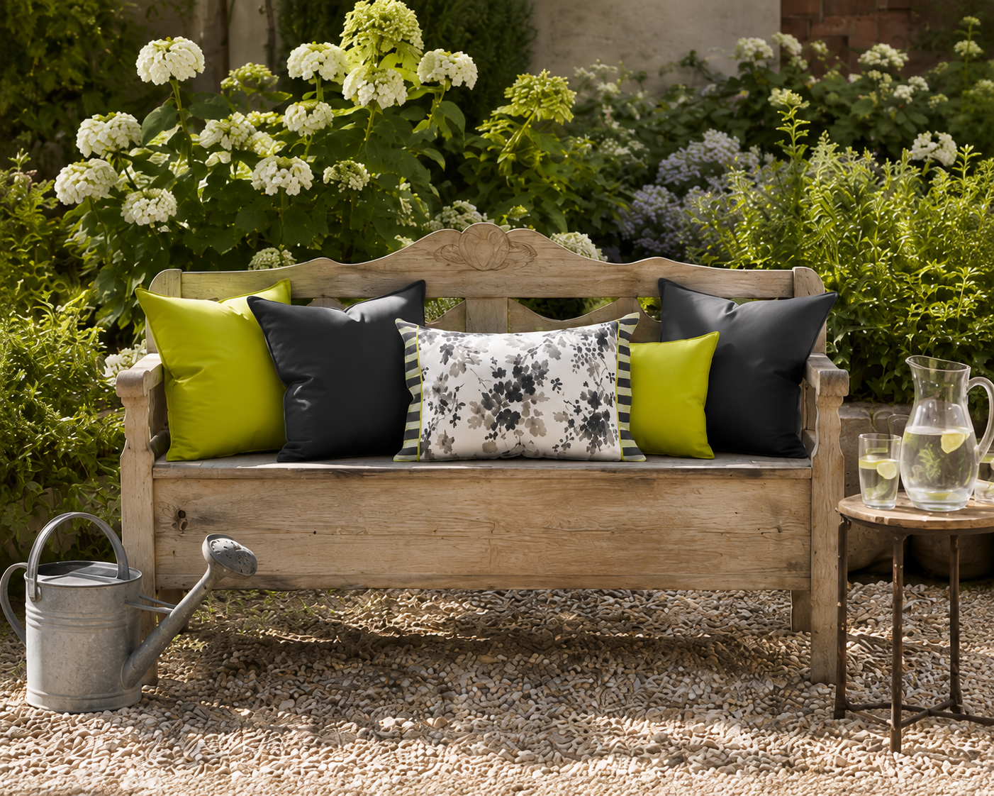 Florales Outdoor-Kissen in Grau, Anthrazit und Weiß mit Limegrün-Akzenten auf einer rustikalen Gartenbank. Stilvolle Kissenkombination für Garten, Terrasse und moderne Outdoor-Wohnbereiche.