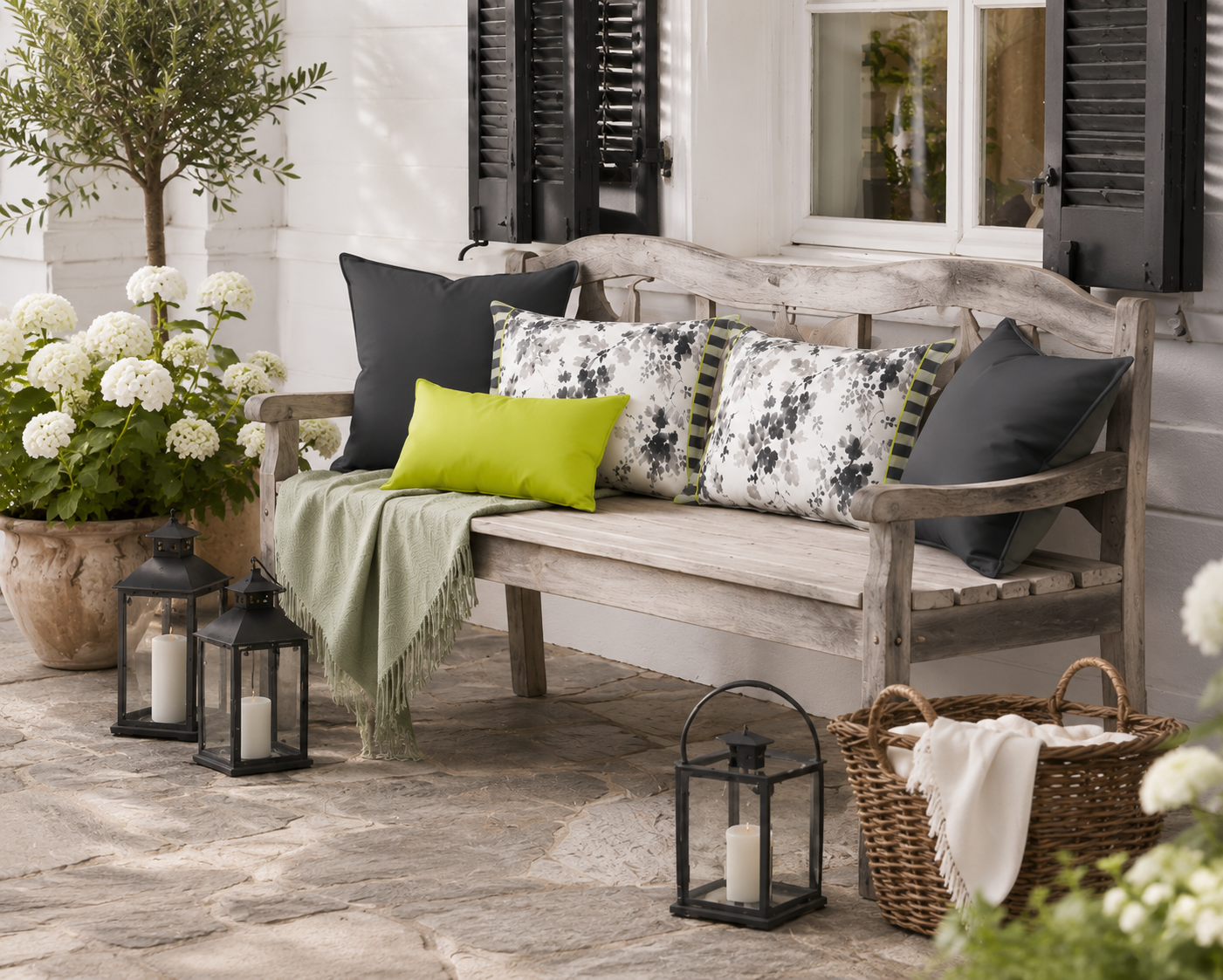 Dekorative Outdoor-Kissen in Grau-Weiß mit floralem Blütenmuster und Limegrün-Akzenten auf einer Holzbank im Garten. Wetterfeste Gartenkissen für Terrasse, Balkon und Outdoor-Lounge.
