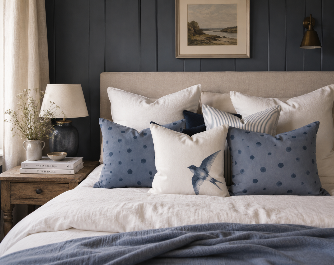 Schlafzimmer mit Kissen der Kollektion Schwalbe & Nebelblau auf einem Bett, kombiniert mit Schwalbendots, Schwalbenkissen, gestreiften Baumwollkissen sowie Kissen in Nebelblau und Graphitblau.