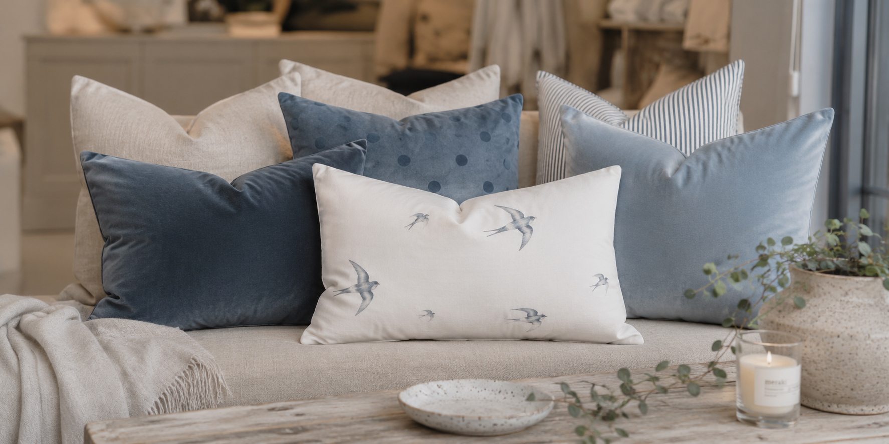 Wohnidee mit einer Kissenkombination in Naturweiß, Nebelblau und Graphitblau. Inspiration zum Kombinieren von Farben, Stoffen und Mustern auf dem Sofa.